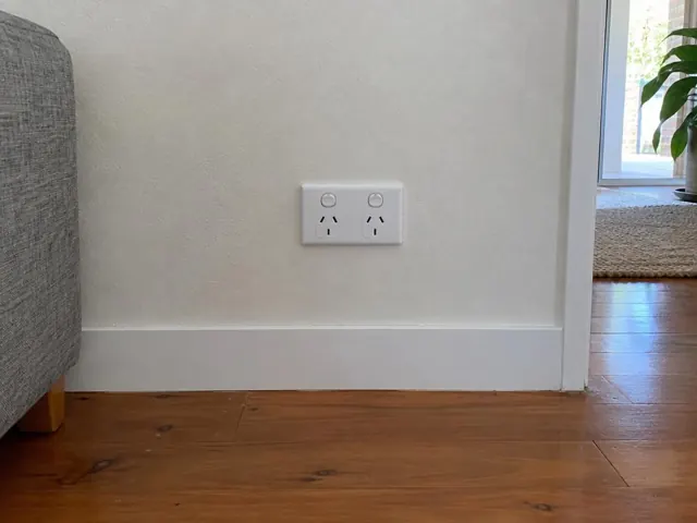 Double power point on a white wall above timber floor with doorway beside it in Tweed Heads