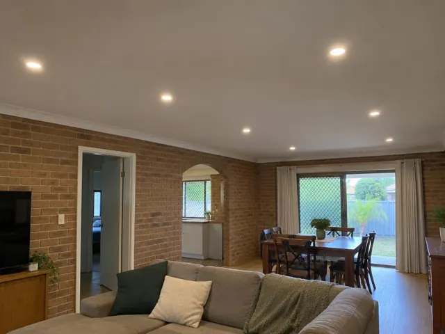 Living room with recessed downlights in a brick home with sliding doors and dining area in Tweed Heads