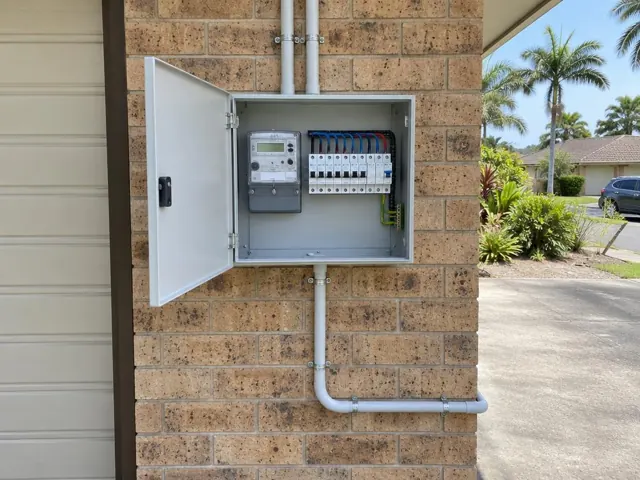 Open switchboard mounted on a brick exterior wall beside a garage in Tweed Heads